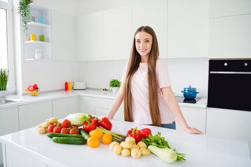 Obraz na płótnie Canvas Portrait of attractive cheerful long-haired girl preparing useful food vegan green salad at home light white kitchen indoors