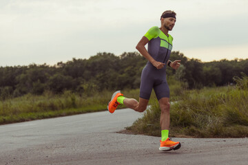 Image of young professional male triathlete, runner in motion on open road. Concept of sport,...