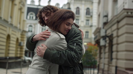 Affectionate couple hugging on street. Man circling woman on city background.