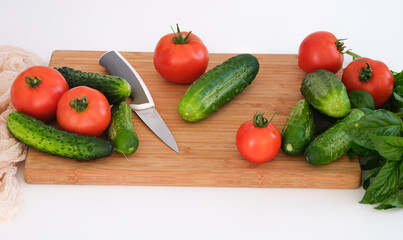 Tomatoes and cucumbers lying on a cutting board ready to be cut