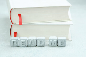 Text Read Me made of gray concrete letters on a white book. Motivation for reading.