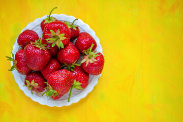 Ripe strawberries on a plate, top view. Berries are a source of vitamins
