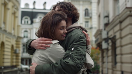 Lovely couple hugging on street. Happy girlfriend leaning to boyfriend outdoor.