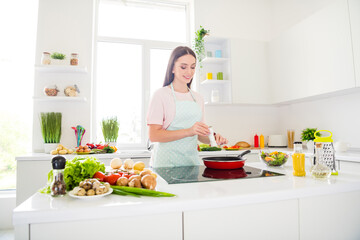 Portrait of attractive cheerful girl adding spices frying omelet cuisine at home light white kitchen indoors
