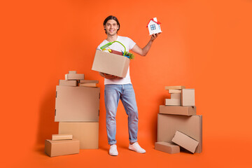 Full size photo of cheerful young happy man hold hand box move house rent isolated on orange color background