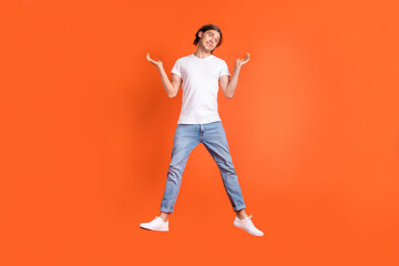 Fototapeta na wymiar Full size photo of young clueless ignorant man jump up shrug shoulders isolated on orange color background