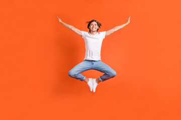 Fototapeta na wymiar Full body photo of cheerful young happy man jump up raise hands enjoy smile isolated on orange color background