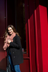 Outdoor autumn portrait of young woman walking in street of European city