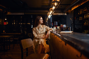Fototapeta na wymiar Alone woman with glass of wine sitting in bar