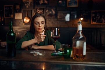 Drunk woman smokes a cigarette at counter in bar