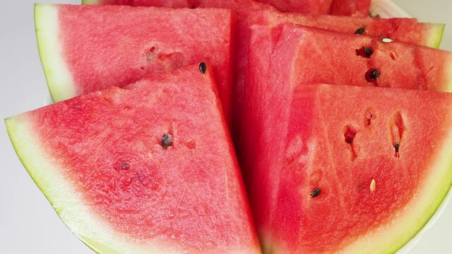 White plate with slices of ripe watermelon. Juice pulp of red sweet watermelon. Video 4k resolution