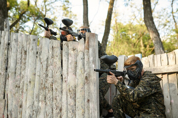 Fototapeta premium Paintball team shoots with guns, military game