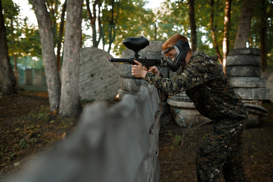 Paintball player aimimg with guns from shelter