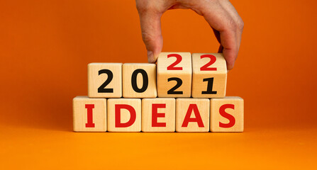 2022 ideas new year symbol. Businessman turns wooden cubes and changes words 'Ideas 2021' to 'Ideas 2022'. Beautiful orange background, copy space. Business, 2022 ideas new year concept.