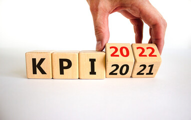 KPI, key performance indicator symbol. Businessman turns wooden cubes with words 'KPI 2021' and 'KPI 2022' on beautiful white background, copy space. Business, KPI, key performance indicator concept.