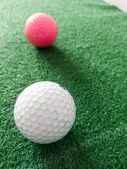 White and pink golf ball on grass.