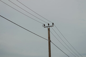 Electric pole with wires against the background of the cloudy sky