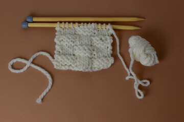 basket stitch hand knitting with super chunky white yarn and wooden needles and knit fabric texture 
