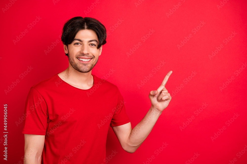 Sticker Photo of positive cheerful guy indicate forefinger empty space wear red t-shirt isolated red color background