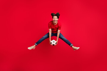 Fototapeta na wymiar Full length photo of young excited man happy positive smile play football sporstman jump isolated over red color background