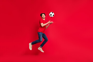 Fototapeta na wymiar Photo of football player guy jump catch throw ball wear red t-shirt jeans shoes isolated red color background