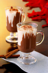 Taças com chocolate quente com canela em fundo de madeira