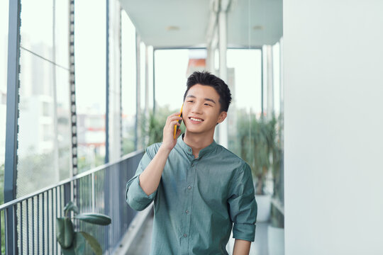 Cheerful young male talking on the phone on a balcony
