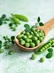 Fresh green peas pods and green peas with sprouts on green wooden background.