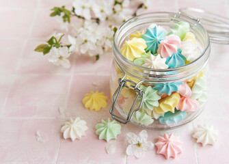 Fototapeta na wymiar Small colorful meringues in the glass jar