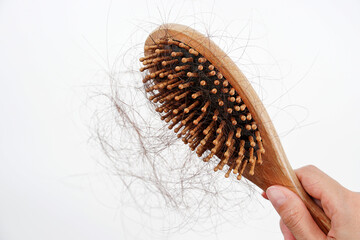 A woman's hand grabs the missing hair on the brush, isolated on white background. hair loss.	
