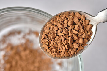 Close up, Freeze Dried Instant Coffee on Tea Spoon with Glass Coffee Cup Background.