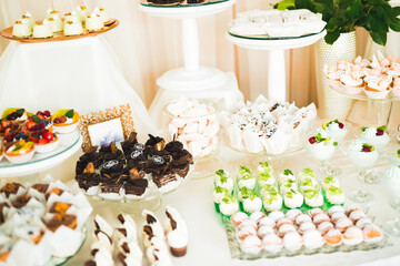 Delicious and tasty dessert table with cupcakes shots at reception closeup