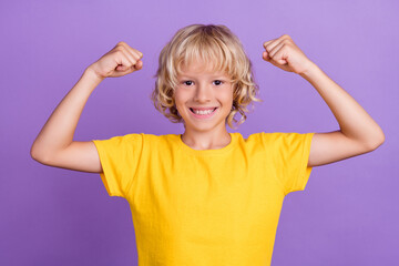 Photo of powerful kid raise hands show biceps muscles wear yellow t-shirt isolated violet color background