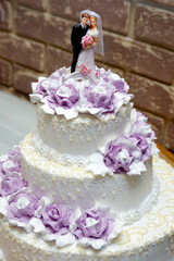 Three-tiered wedding cake white-lilac with bride and groom figures