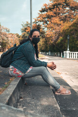 latin woman sitting with black mask and backpack