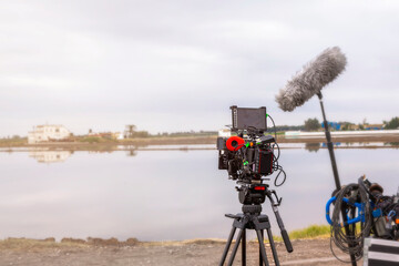 Film camera, microphone and audiovisual equipment in front of a lake on a cloudy day. Film concept, audiovisual and making of