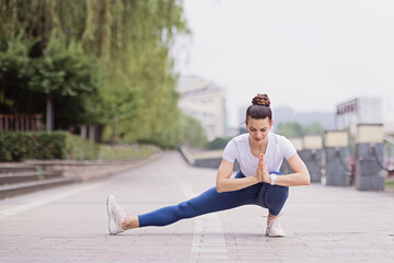 Portrait of happy young caucasian woman exercising yoga outdoors early morning. Beautiful girl practicing asana in park at summer