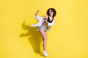 Full length body size photo of funky girl wearing stylish clothes laughing dancing isolated on bright yellow color background