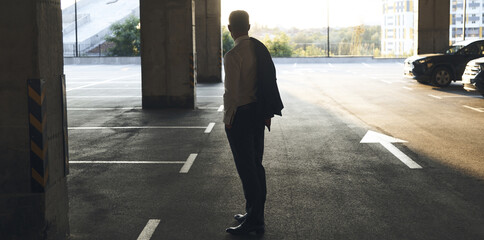 Rear view of mature man in formalwear standing on parking lot