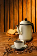 Photo sur Plexiglas Café Mesa de madeira com xícara de café e bule rústico com grãos de café espalhados ao redor e torradas ao fundo