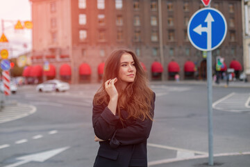 Fototapeta premium Young beautiful brunette woman walking in the street in city centre at sunrise time
