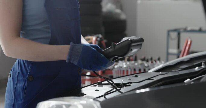 Female mechanic testing a car battery