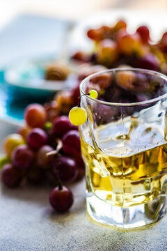 Glass of Georgian chacha brandy next to a bunch of red grapes on a table