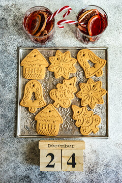 Two glasses of mulled wine and a tray of gingerbread Christmas cookies on a  metal tray with a 24 December calendar