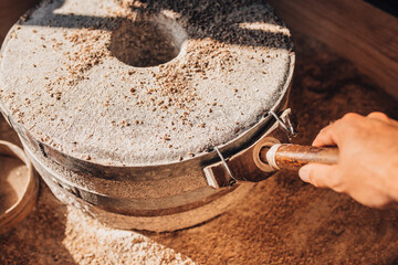 Grind grain into flour using a mechanical stone mill in the old way