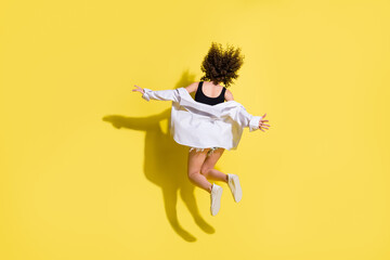 Full size back photo of optimistic cool girl run wear top shirt sneakers isolated on yellow...