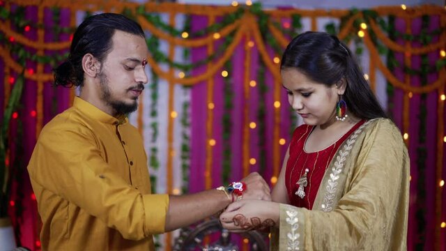 Sister tying the rakhi, Raksha Bandhan to brother's wrist during festival or ceremony - Raksha Bandhan celebrated across India as selfless love or relationship between brother and sister.