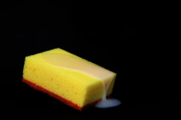 A yellow sponge on which liquid soap flows, a black background. Space for text and design