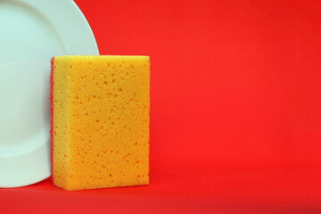 White dish sponge on a white plate background with a bright red background, a place for your text