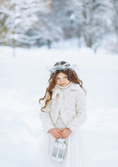 Fototapeta na wymiar Adorable little girl holding Christmas lantern outdoors on beautiful winter snow day